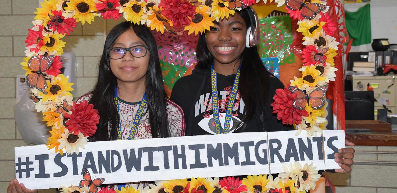 Two students supporting the Dreamers Club with an I Stand With Immigrants sign.