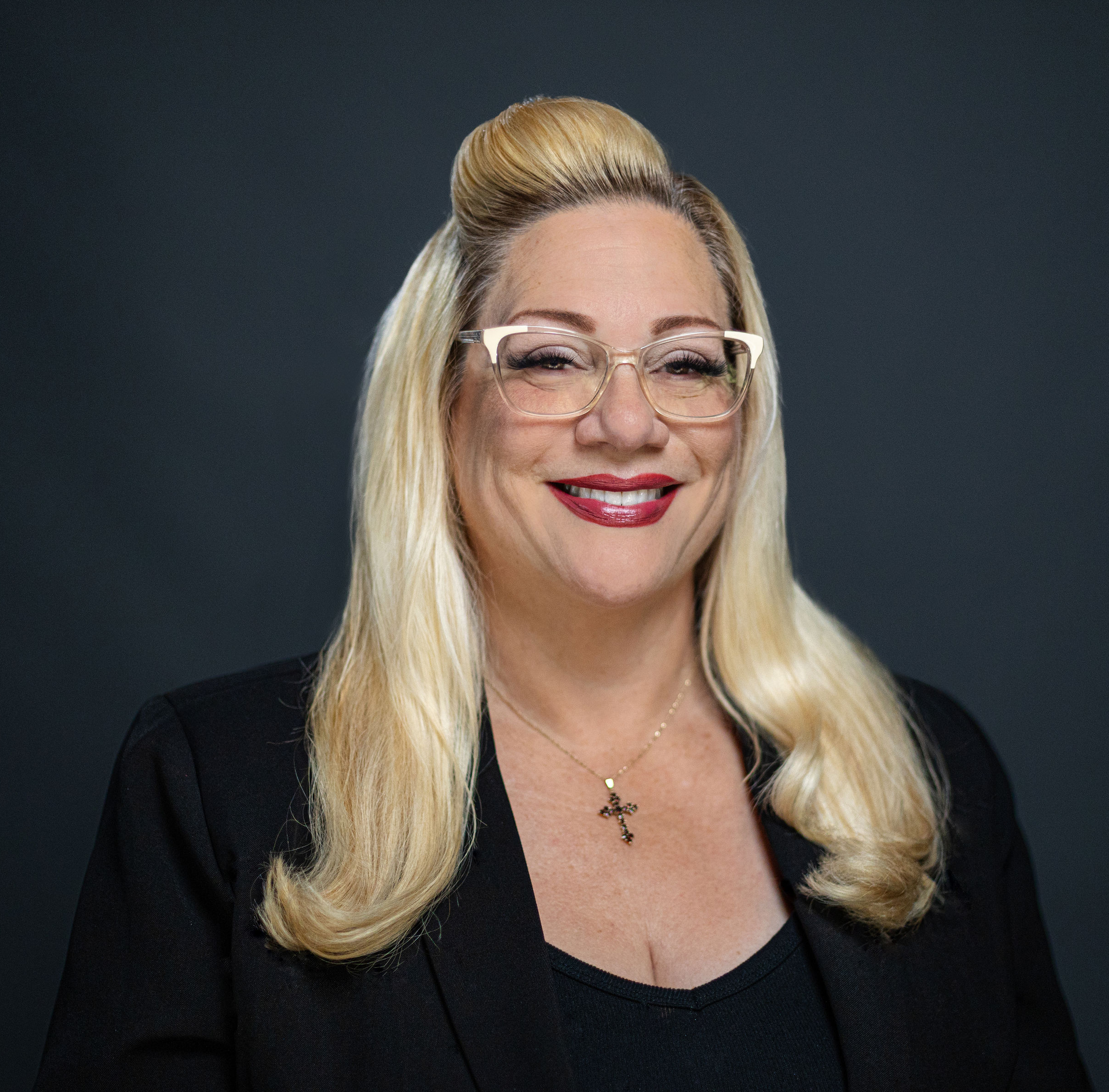 Woman with blonde hair smiling in a black top.