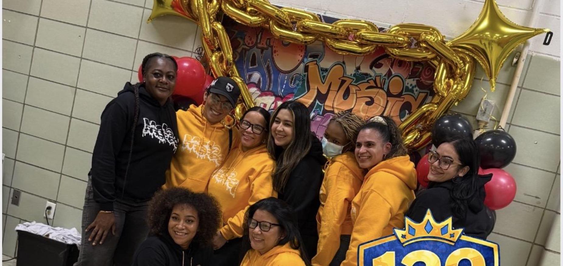 Group of MS 129 staff wearing black and gold hoodies