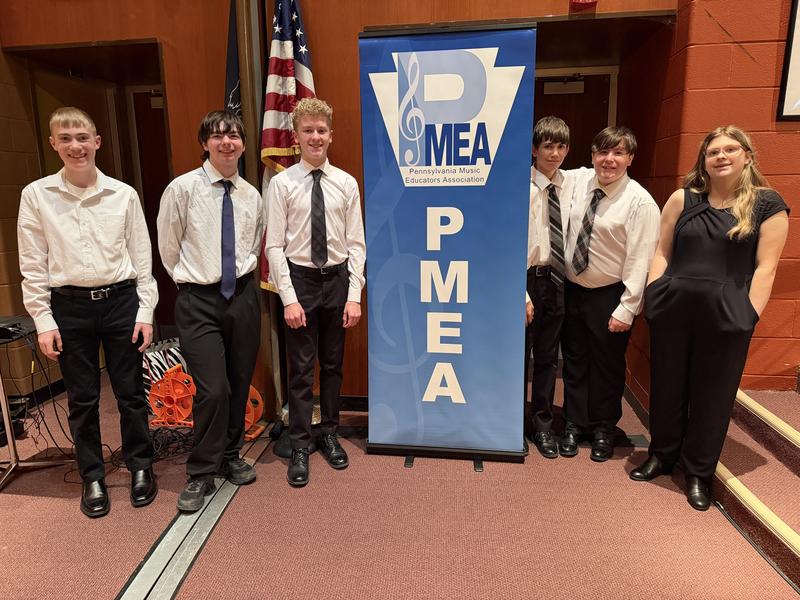 students dressed in black and white next to PMEA sign
