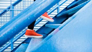 Person wearing red shoes walking up blue stairs