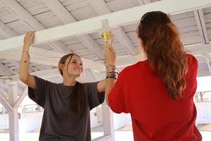two students happily paint a white beam in a livestock barn