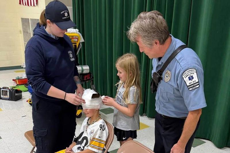 At Harrison Park, EMT Alexis Clayton and Paramedic Mike Keszer demonstrate the use of dressings to stop bleeding with students Rowen Sullivan and Jade Snyder