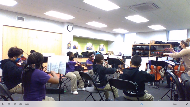 Image shows scholars playing violin in the classroom
