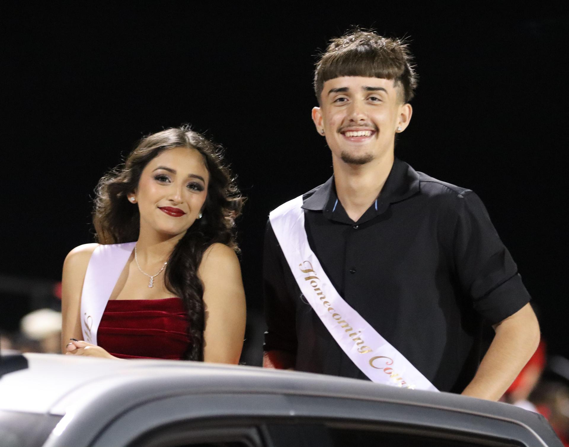 homecoming king and queen candidates entering the stadium in trucks