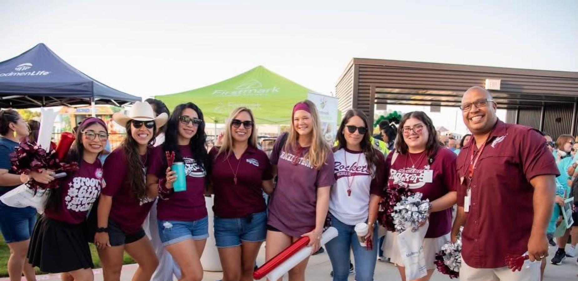 Group of people wearing maroon shirts and enjoying an outdoor event.