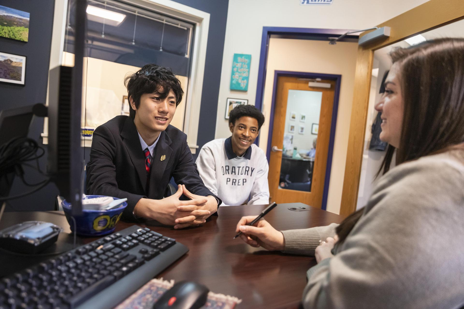 College counselor reviewing college guides with three smiling students