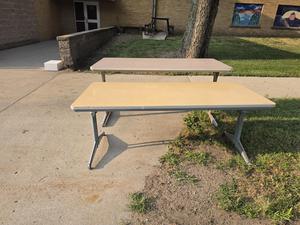 Two tables on a concrete surface with grass nearby