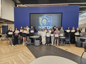 high school students standing in the cafeteria holding their certficiates
