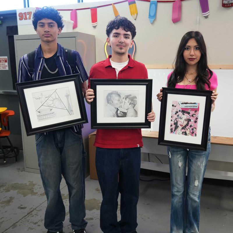 3 students holding their winning artwork