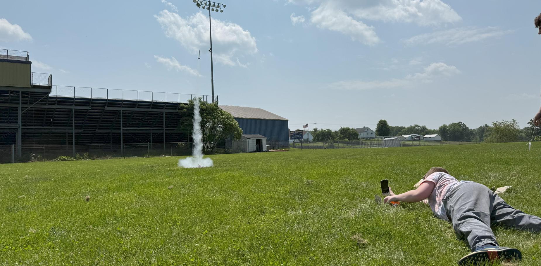 kid lying on the ground in grass and launching a rocket
