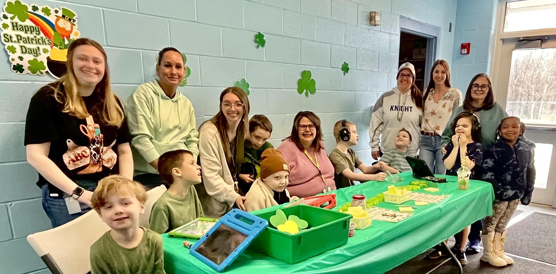 Group of adults and children at a table decorated for a festive event.