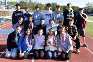 A group of students wearing leis gathers on the track for a photo.