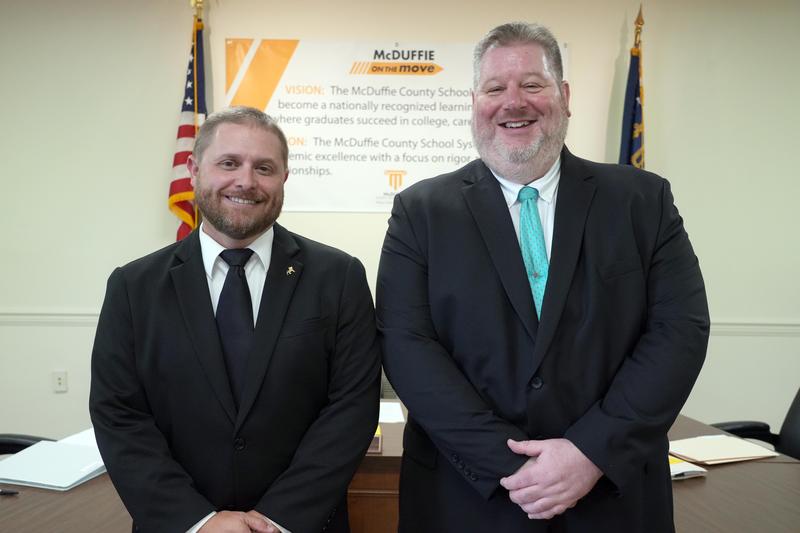 New principals Brock Hawkins and James Meneguzzo pose in the board of education meeting room.