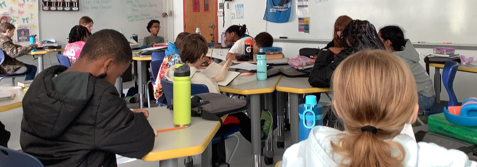 Students engaged in reading and studying in a classroom setting.