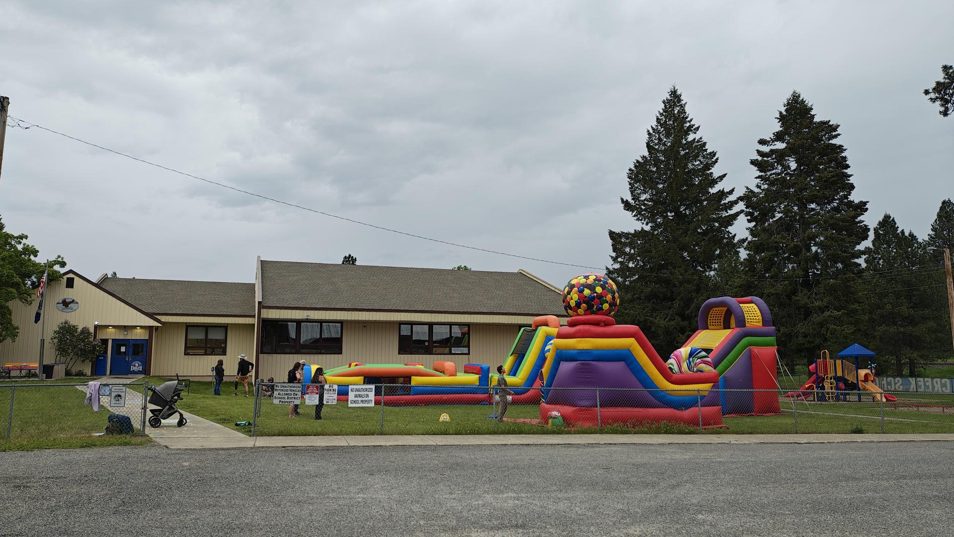 Outdoor view of a school with a large inflatable slide and children playing.