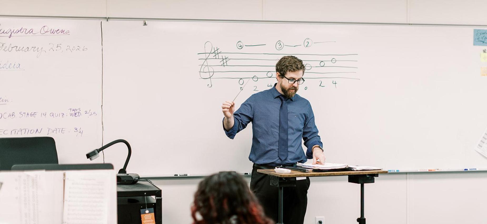 Music teacher conducts a lesson at the whiteboard
