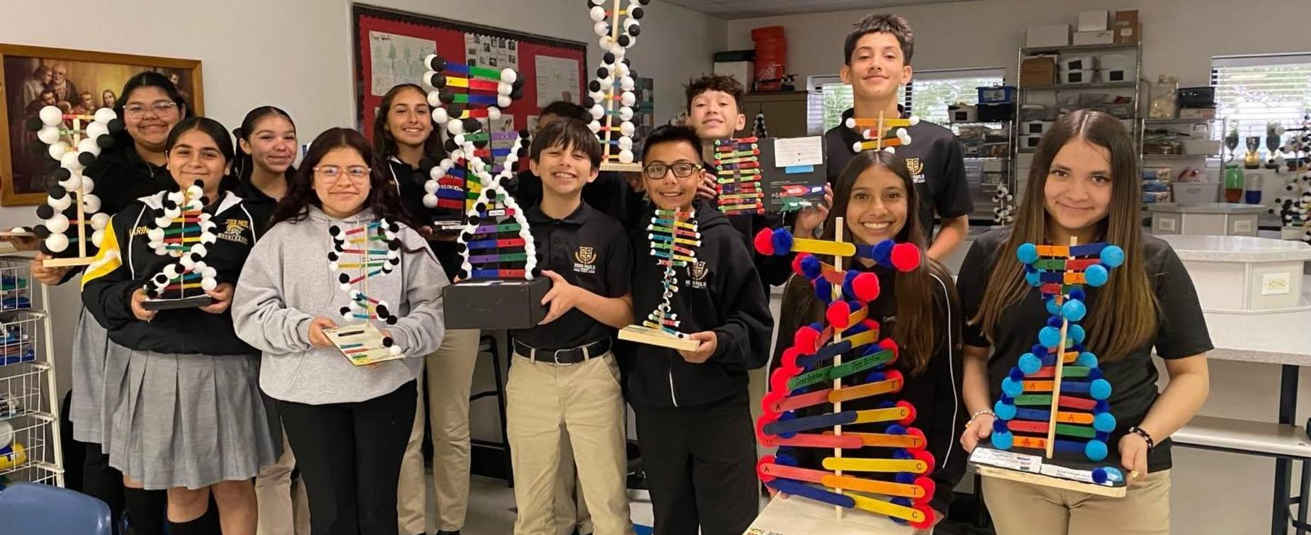 A group of students proudly displaying colorful science projects in a classroom.