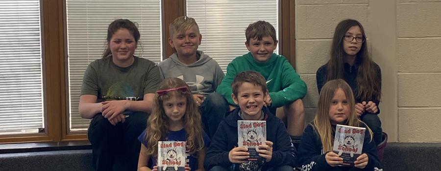 Students showing the book Sled Dog School.