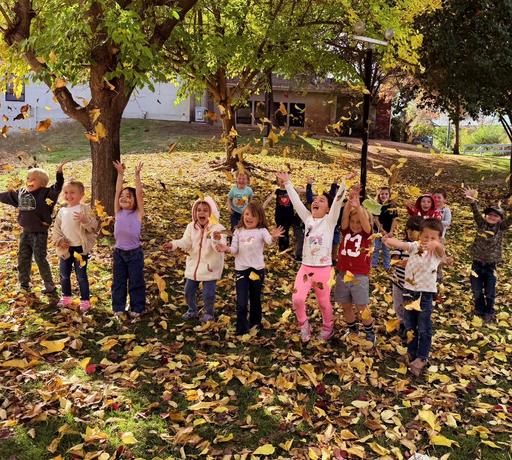 picture of elementary students playing in the Fall leaves
