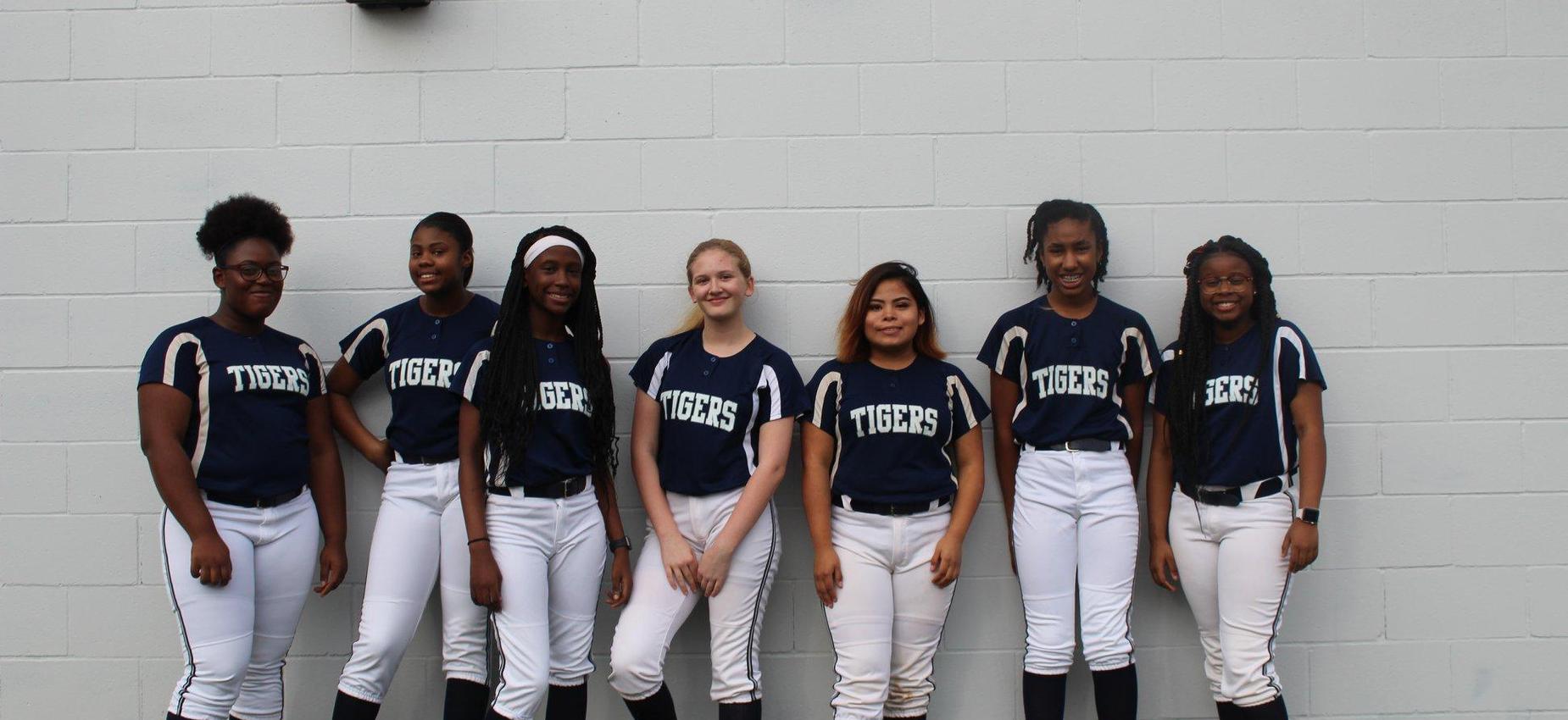 girls baseball team lined up against a wall