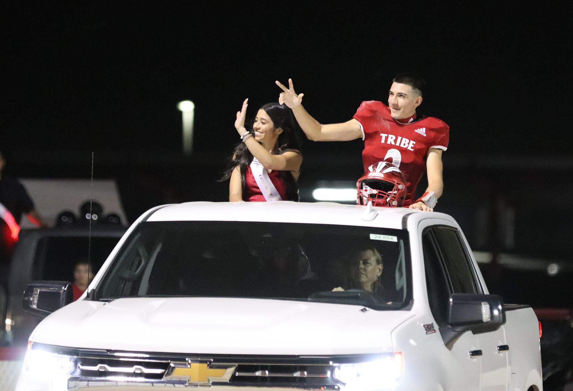 homecoming king and queen candidates entering the stadium in trucks
