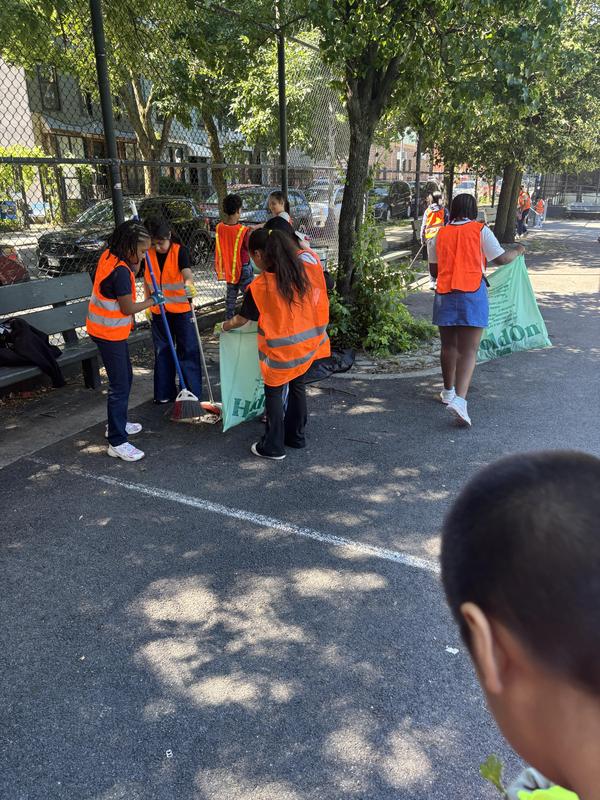 Students cleaning up with brooms and bags