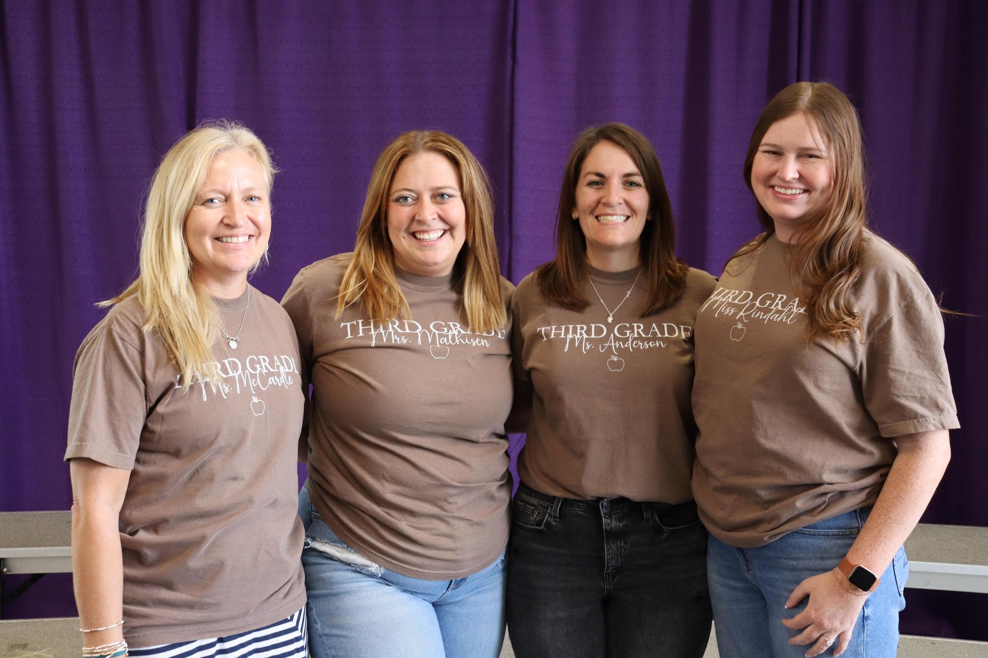  The Third grade teachers, wearing matching shirts and smiling for a picture. 