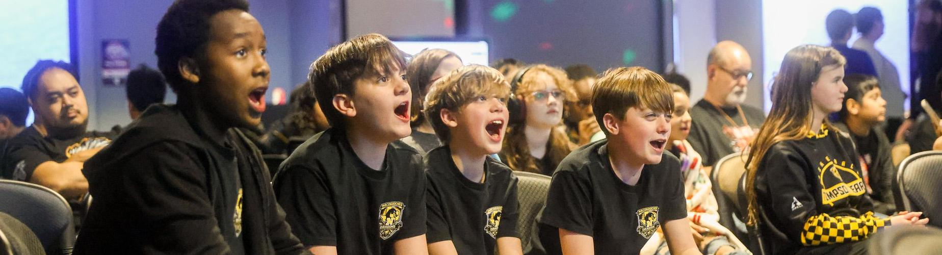 Excited group of children and teens watching an event, cheering with enthusiasm.