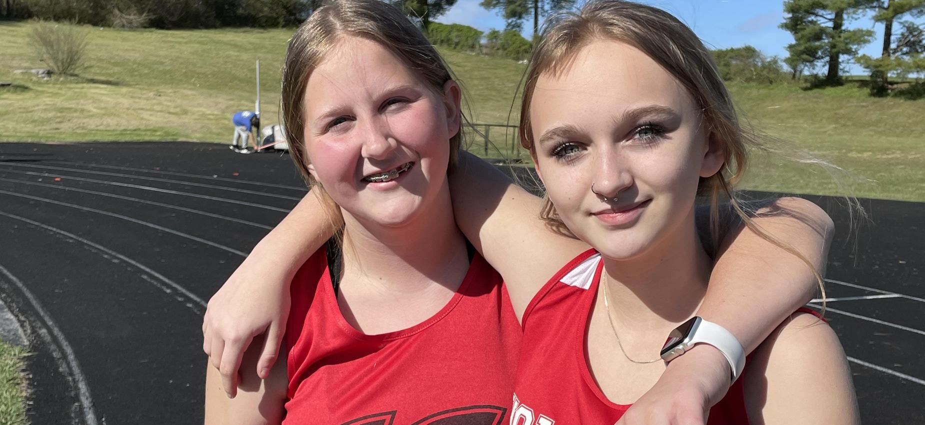 Two athletes pose on a track.
