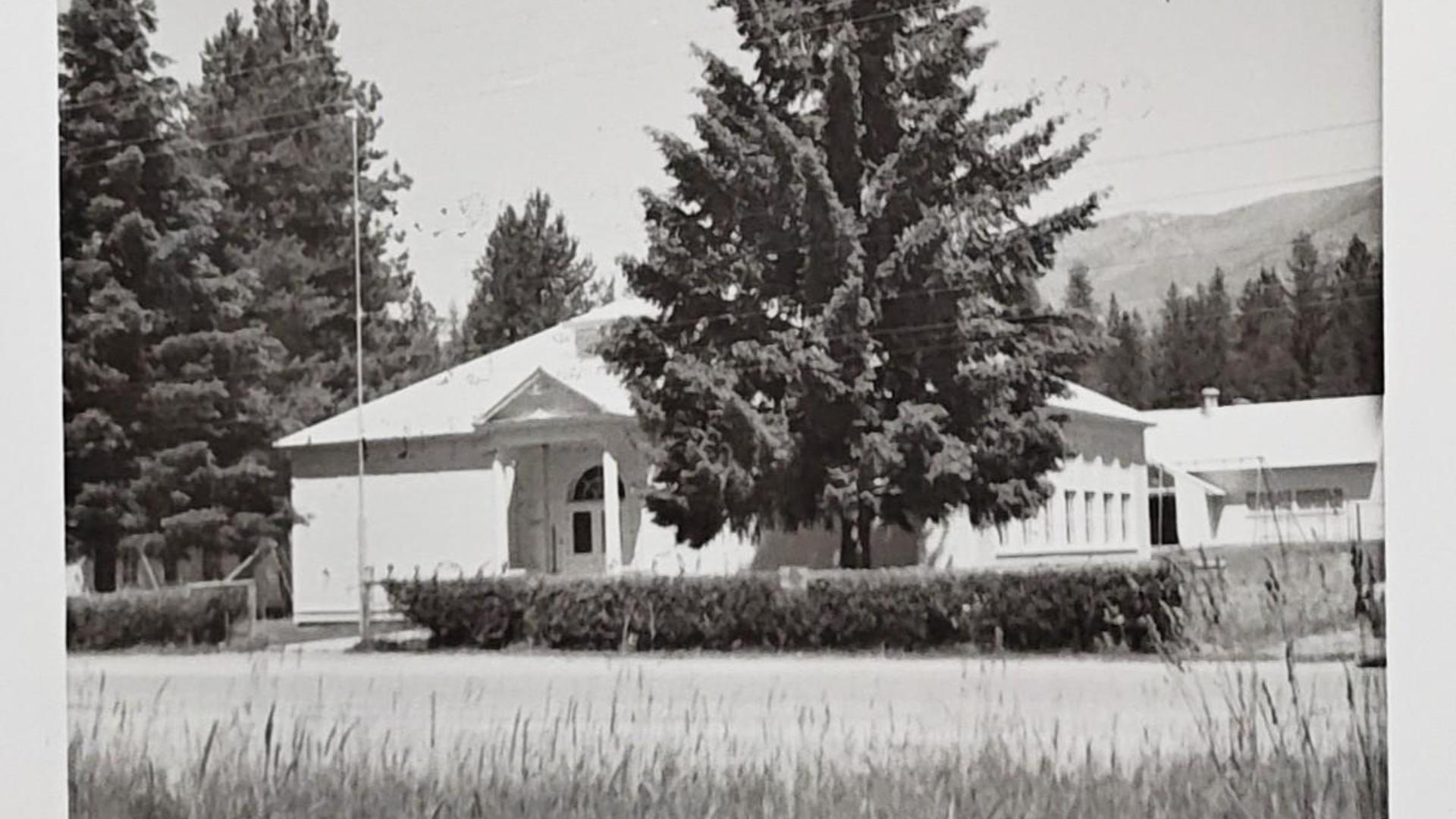 Black and white image of a school building surrounded by trees.