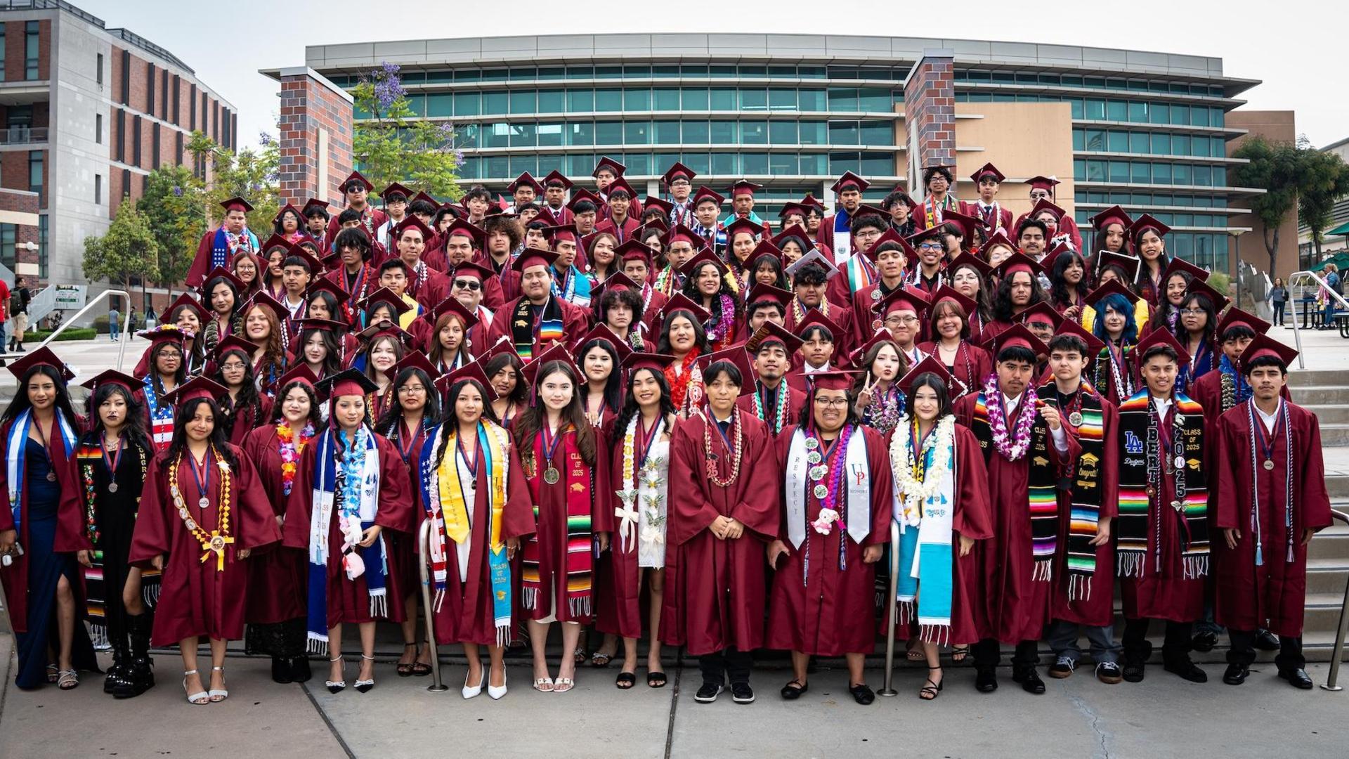 A large group of graduates in caps and gowns poses for a group photo.