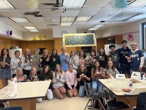 class standing in school kitchen holding cookies