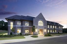 Modern two-story building with stone accents and large windows at dusk.