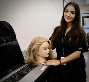 Female student standing next to a cosmetology manikin
