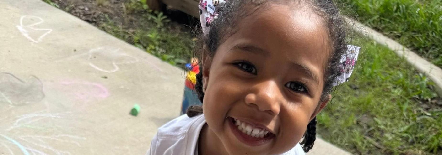 Child smiling on sidewalk
