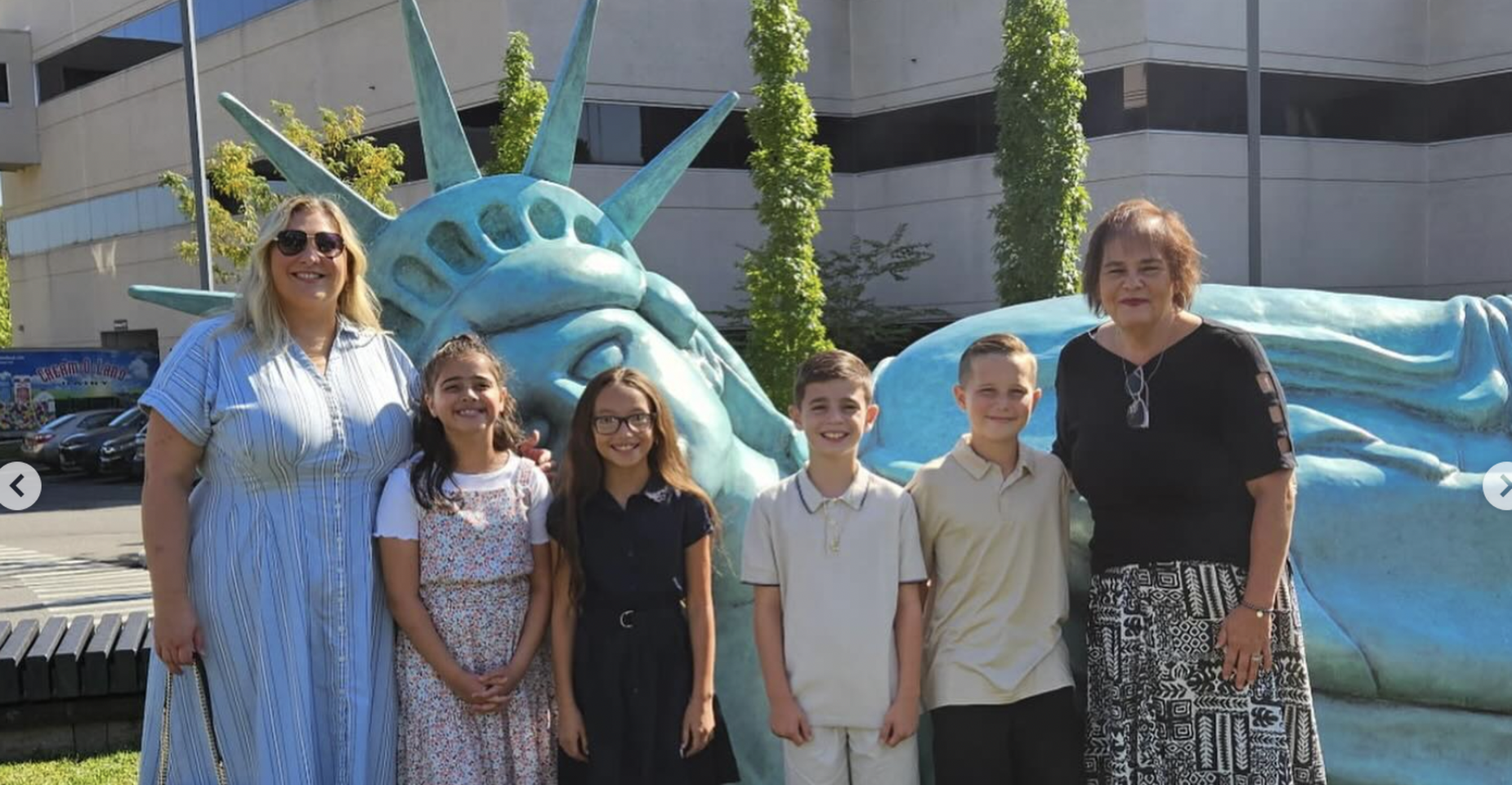 Group of five people standing beside a large statue of the Statue of Liberty.