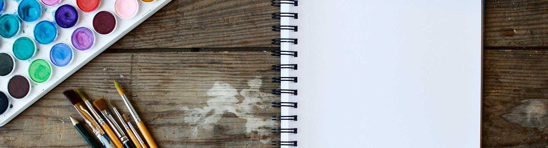 Notebook and watercolor supplies on a table