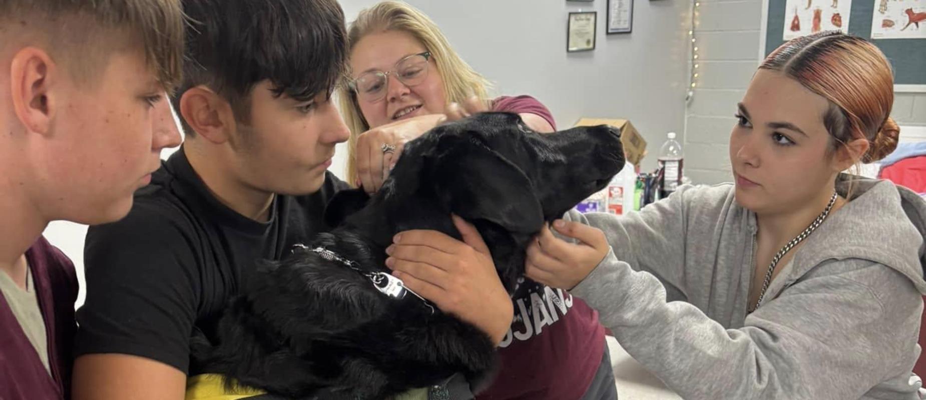 Vet Tec students learning to examine pet therapy dog Charlie