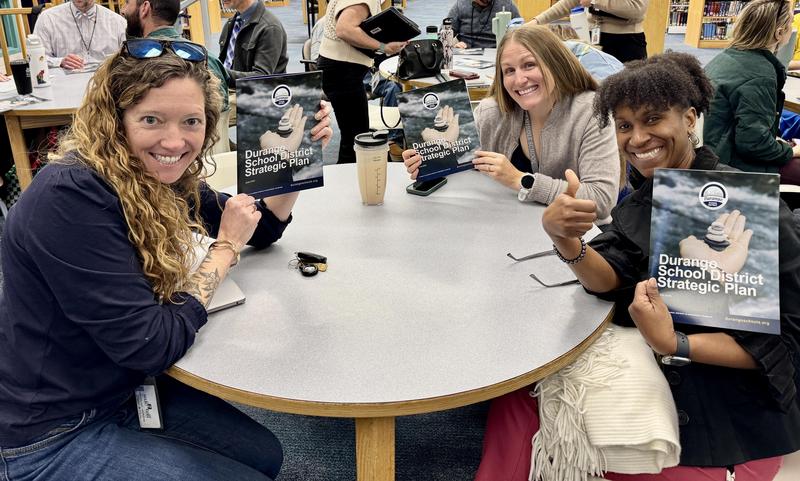 Group of people sit around a table and show Strategic Plan