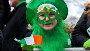 Child celebrating St. Patrick's Day wearing green attire, oversized glasses, and a shamrock beard.