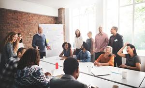 A diverse group of people engaged in a lively meeting in a bright conference room.