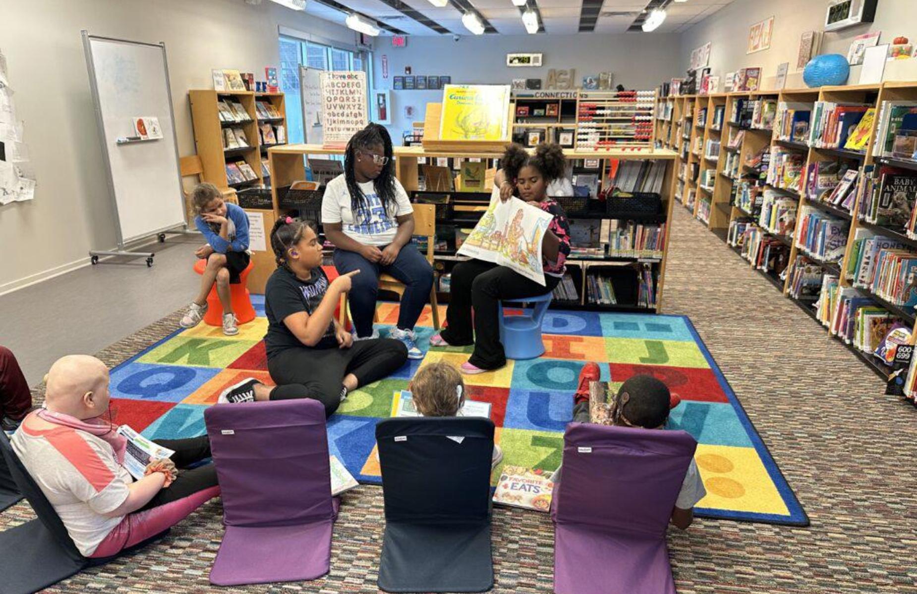 Children and adults engage in a storytelling session in a colorful library setting.