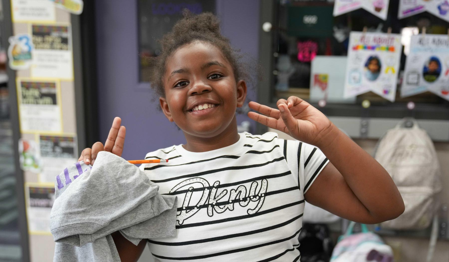 Girl smiling and making peace signs with both hands