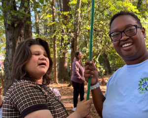 student and staff smiling at camera, holding a green rope
