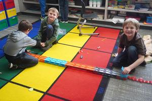 Three boys race cars down a track.