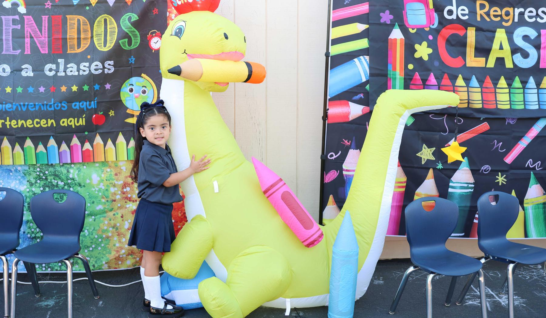 girl standing next to inflatable dinosaur