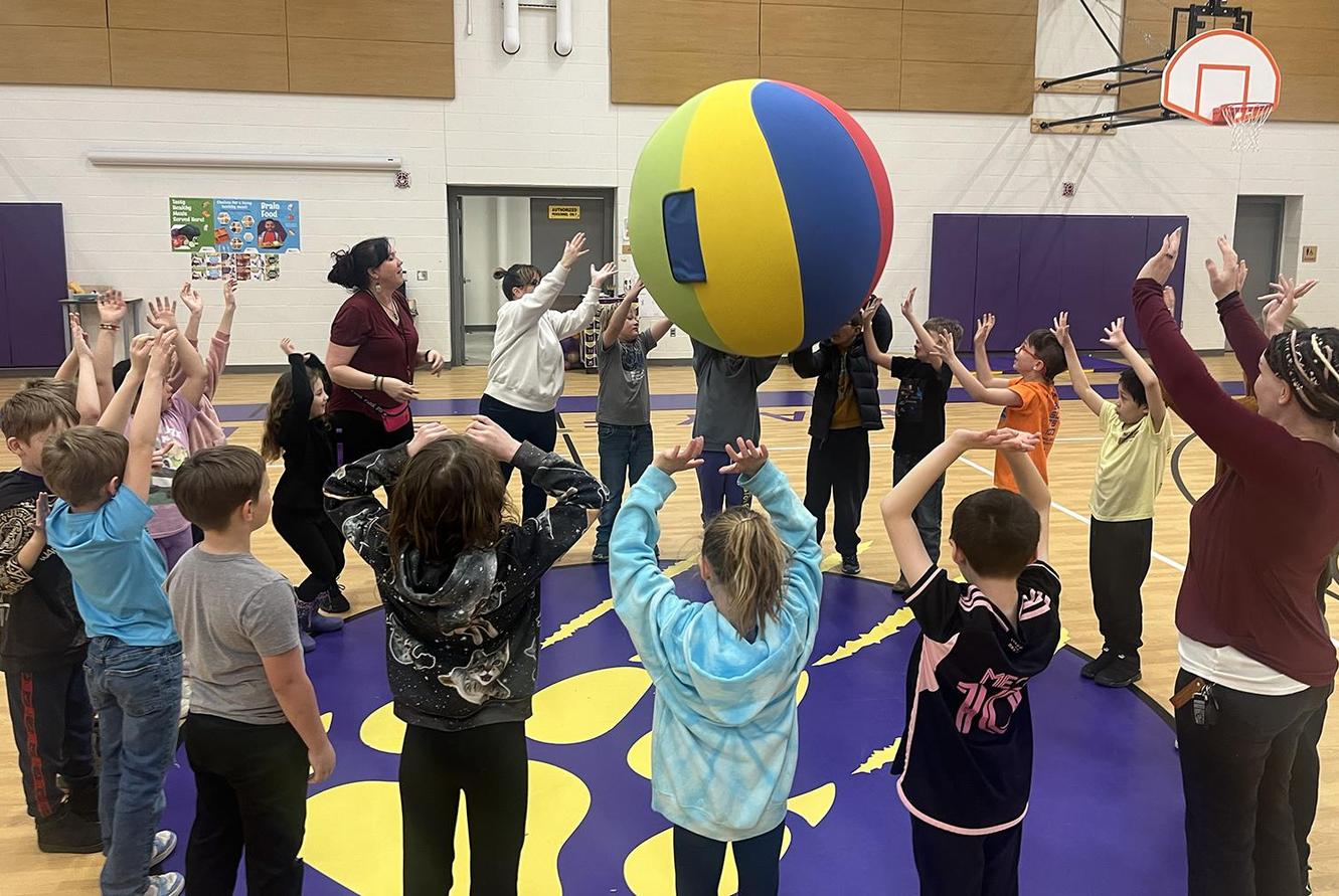 Students pass a giant ball in a circle.