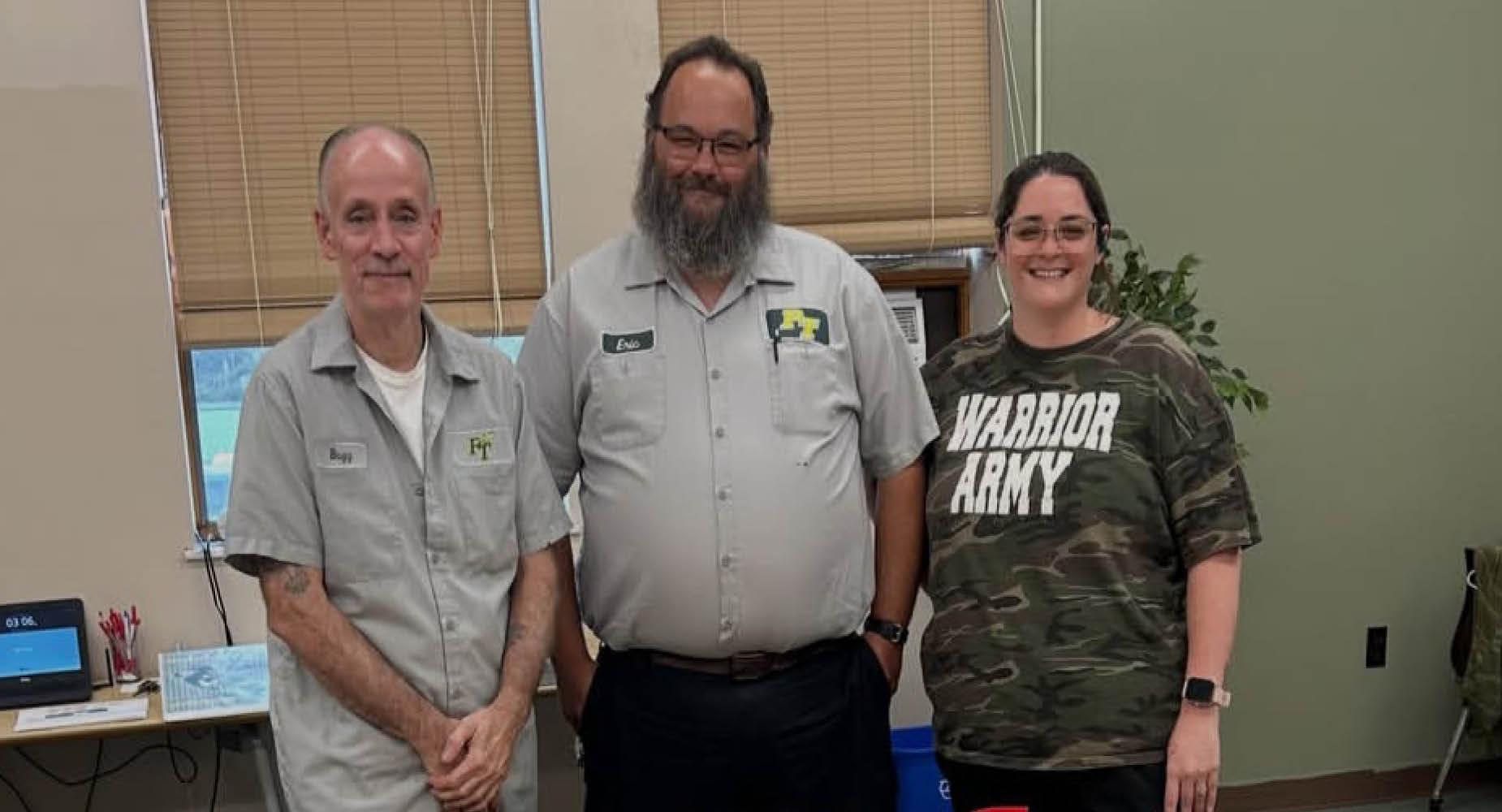 Three educators posing together in a classroom setting.