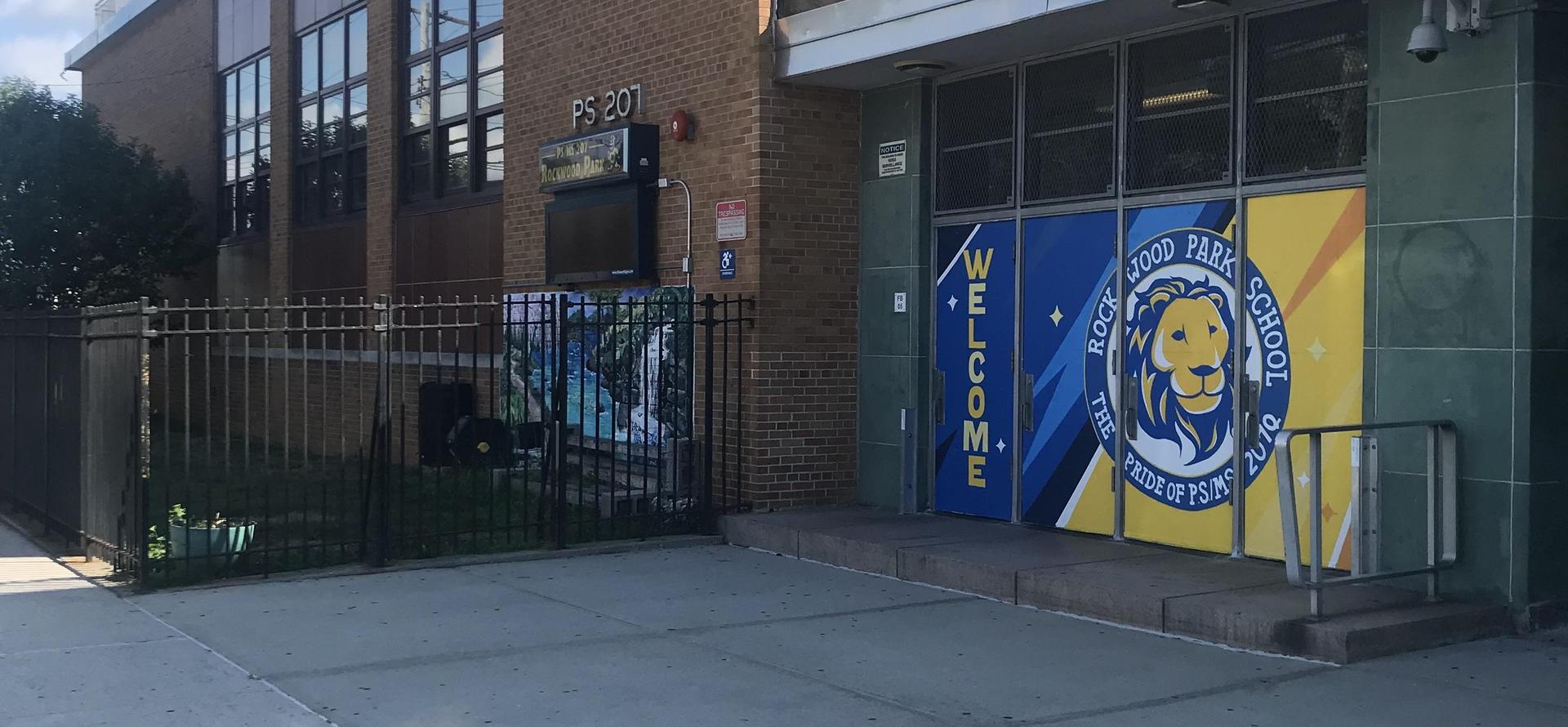 School entrance with colorful doors and a welcome sign.